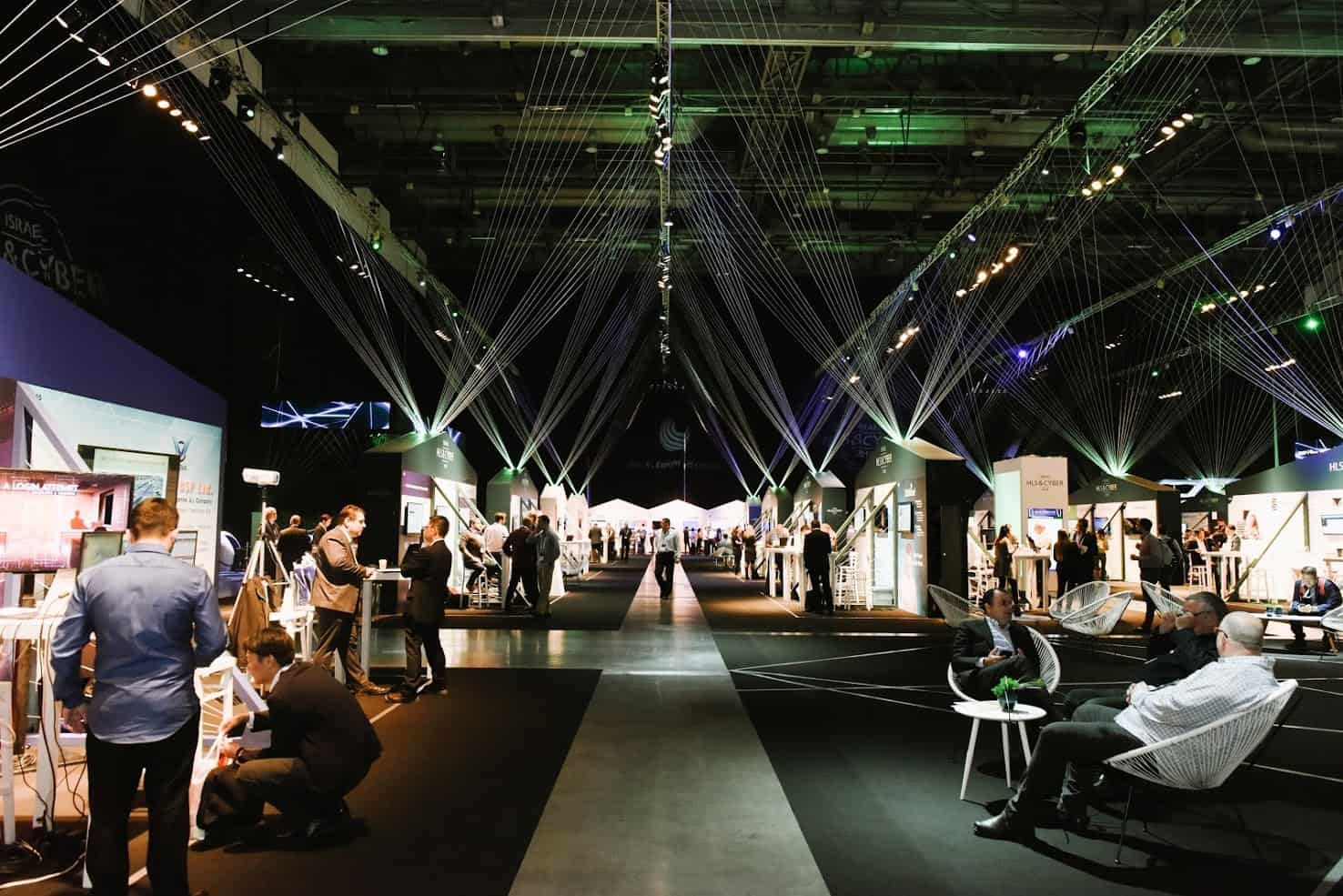 צילום מתוך תערוכה מקצועית בביתן של אקספו תל אביב. בתמונה נראים דוכני תצוגה מודרניים, קהל מבקרים ואפקטים של תאורה ישרה המקנים אווירה טכנולוגית וחדשנית.